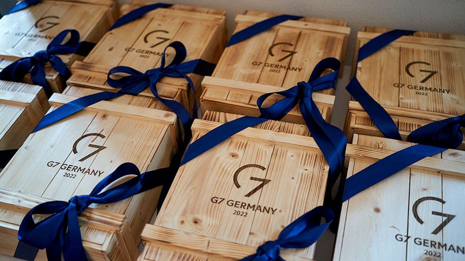 Holzkisten mit Aufdruck G7 Germany 2022, verziert mit je einer dunkelblauen Schleife