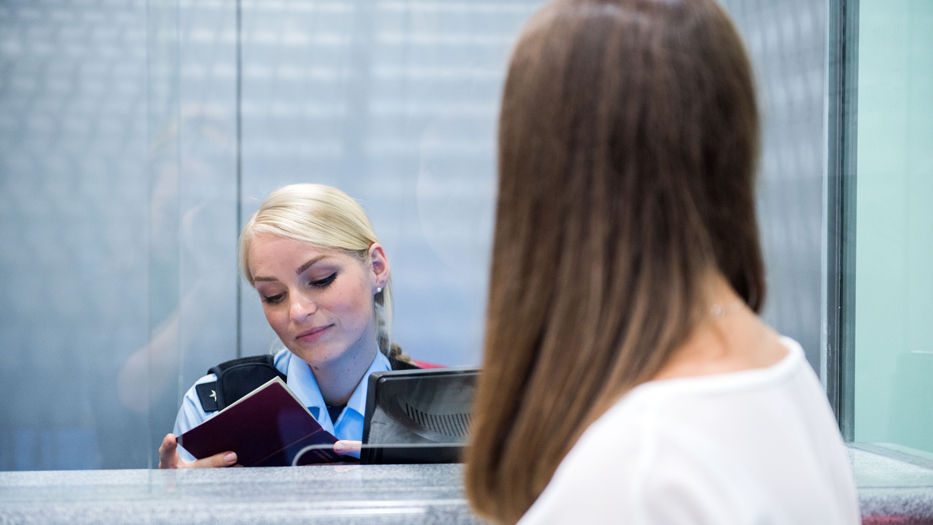 Eine Polizistin kontrolliert eine einreisende Person am Flughafen