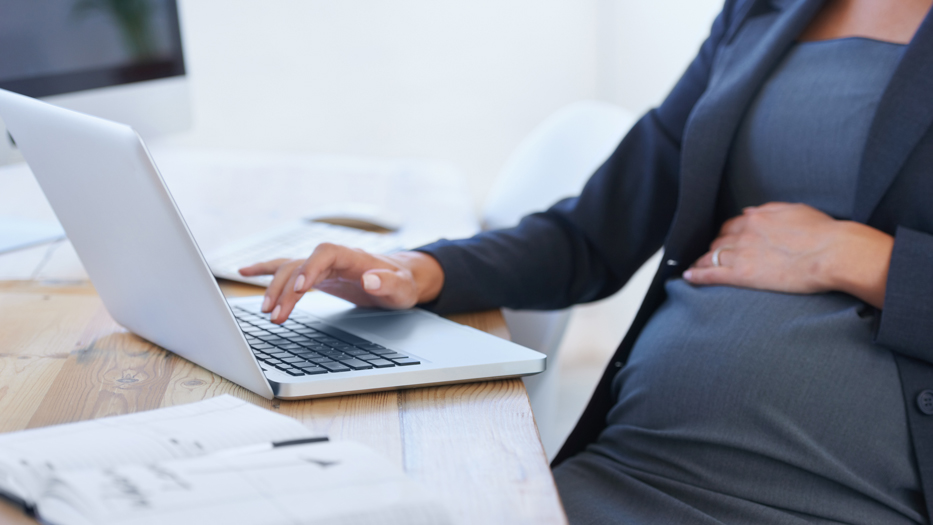 Eine schwangere Frau beim Arbeiten am Laptop