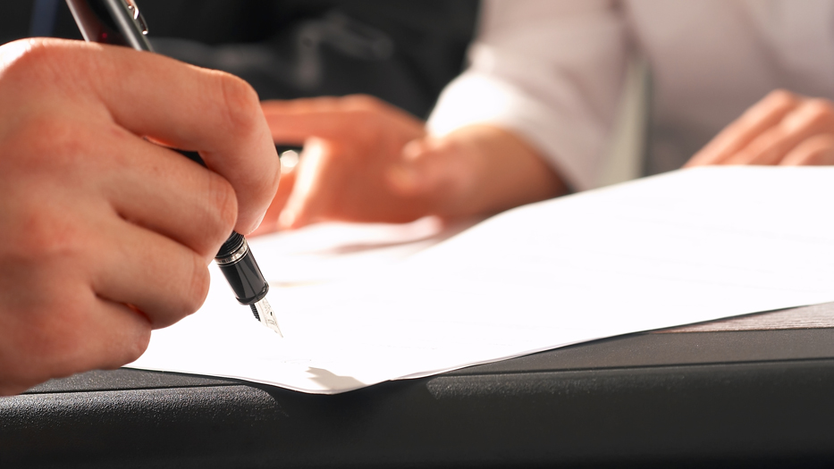 Hand mit Füller unterschreibt ein Dokument