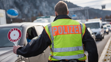 Ein Polizist stoppt mit einer Polizeikelle ein Auto auf der Autobahn