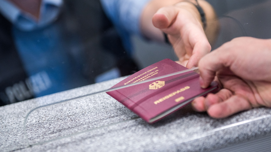 Ein Beamter kontrolliert einen deutschen Reisepass