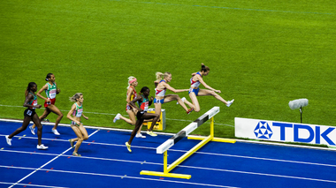 Sportlerinnen springen über eine Hürde