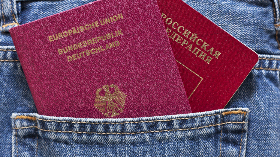 Deutscher und russischer Reisepass gucken aus einer Hosentasche heraus