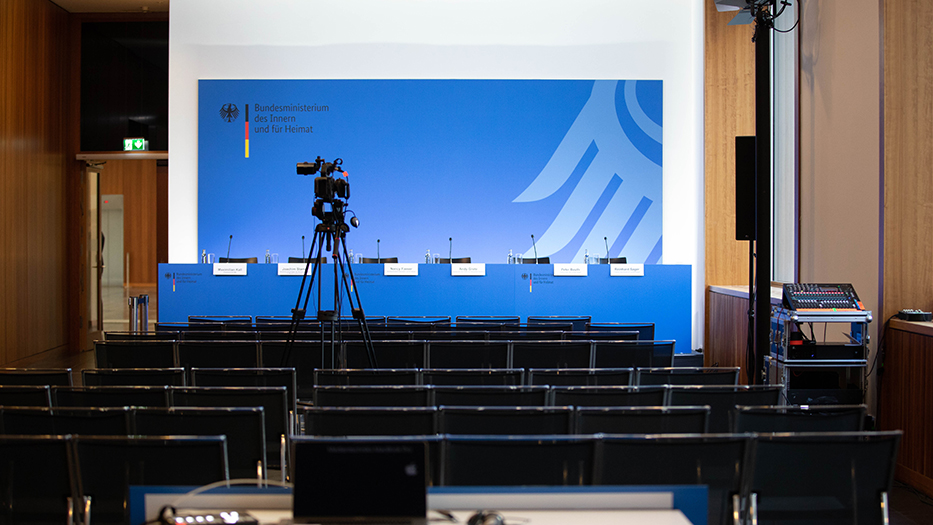 Pressekonferenztisch vor blauer Pressewand im BMI