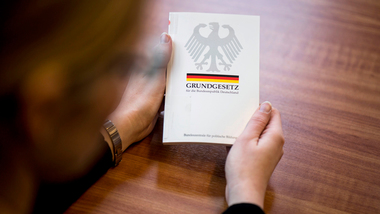 Eine Person hält das Grundgesetz in den Händen