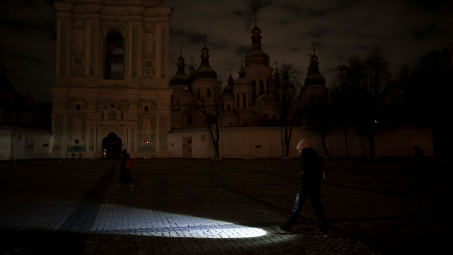 A woman lights the way with a flashlight during a power outage in Kyiv